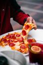 Close-up of a hand pulling a cheesy pepperoni pizza slice, perfect for food lovers.
