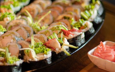 An elegant display of assorted sushi on a black platter with wasabi and ginger.