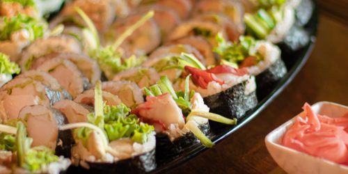 An elegant display of assorted sushi on a black platter with wasabi and ginger.