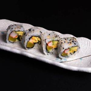 Tempting sushi rolls with avocado and crab sticks on a stylish ceramic plate.