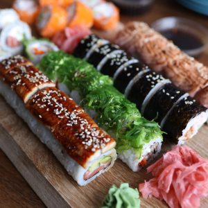 A delicious selection of sushi rolls with toppings like seaweed and sesame seeds on a wooden platter.