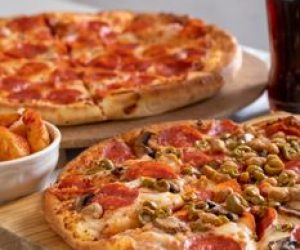 Close-up of pepperoni and veggie pizzas with soda, perfect for a casual dining experience.